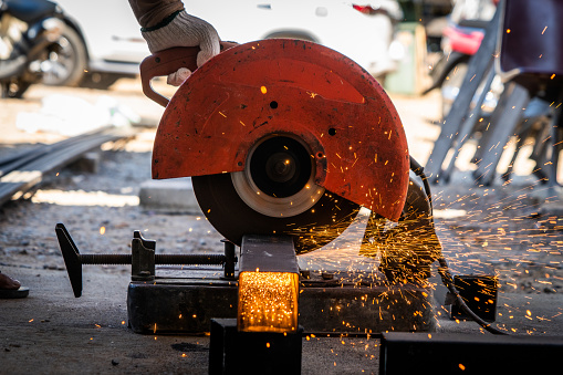 Table saw being used to cut metal with sparks flying around the construction site.