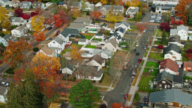 Aerial establishing shot of a residential neighborhood in Stamford, Connecticut on a sunny day in Fall, looking down on houses and vibrant autumn leaf color on the trees.