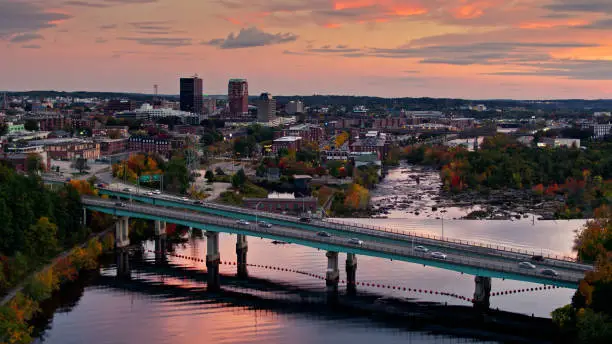 Aerial establishing shot of Manchester, New Hampshire in Fall, with a colorful sunset sky. On the bank of the Merrimack River is the Millyard, formerly the Amoskeag Manufacturing Company.     

Authorization was obtained from the FAA for this operation in restricted airspace.