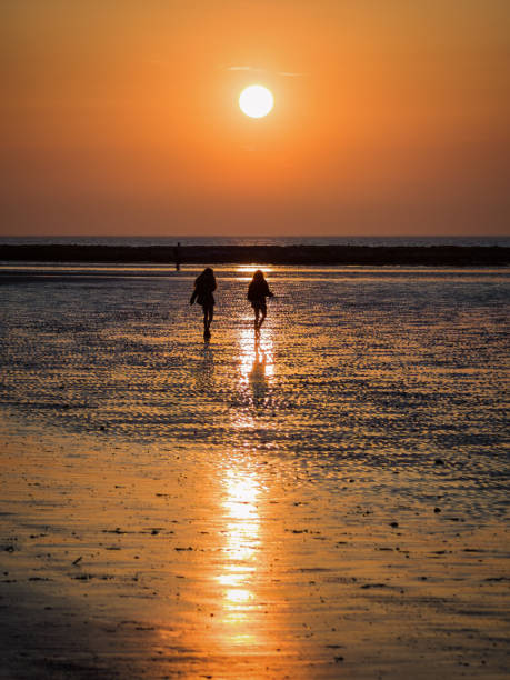 Two people strolling into a beach sunset stock photo