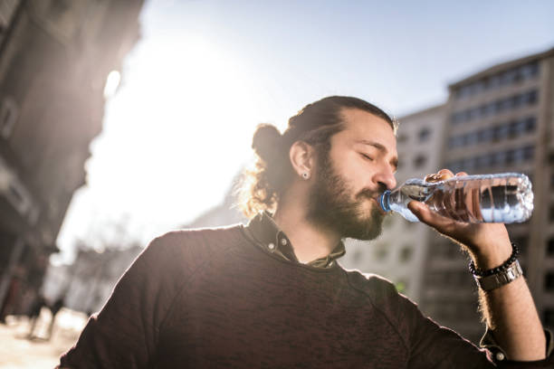 istock Young man drinking water in the city. 1365950200