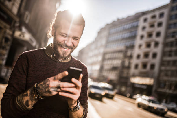 istock Young man using phone in the city and laughing. 1365950820