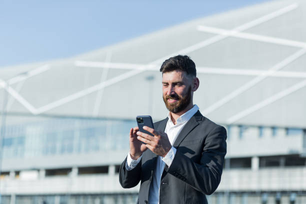 istock Successful businessman with beard uses phone outside office 1365954542