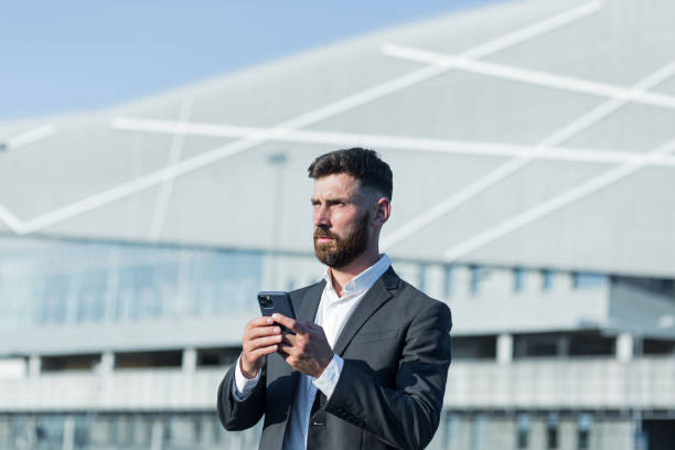 istock Successful businessman with beard uses phone outside office 1365954548
