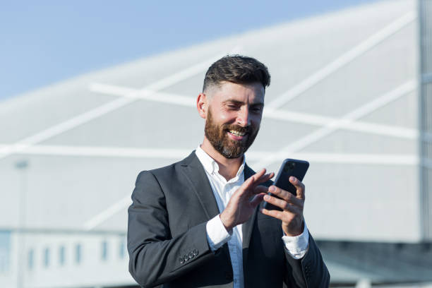 istock Successful businessman with beard uses phone outside office 1365954550