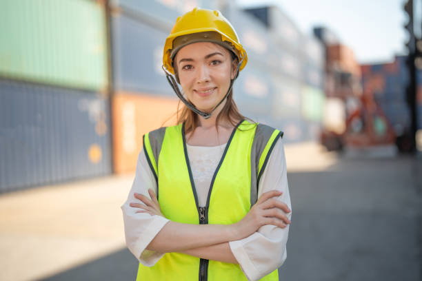 istock factory woman worker is standing with confident with working suit green reflect for safety dress in front container cargo. Concept of smart industry worker operating of shipping transportation. 1365959227