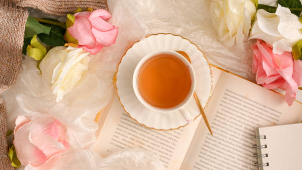 istock Top view of a beautiful feminine workspace with novel book, tea cup 1365965359
