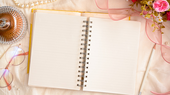 Opened blank notebook on beautiful pink and white feminine workspace concept. overhead shot