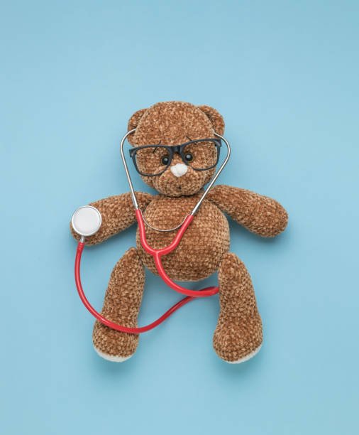 istock A knitted teddy bear with glasses and a red stethoscope on a blue background. 1365965457