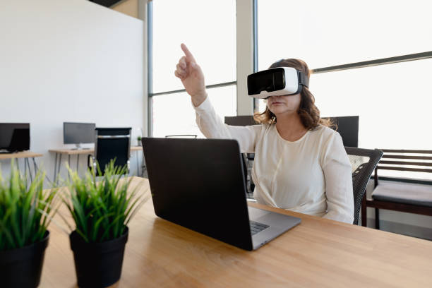 istock Senior woman in the office using VR glasses 1365965723