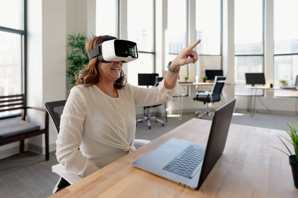 istock Senior woman in the office using VR glasses 1365965727