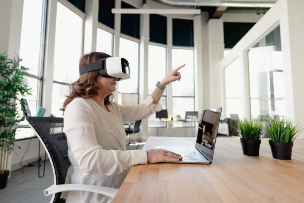 istock Senior woman in the office using VR glasses 1365965731