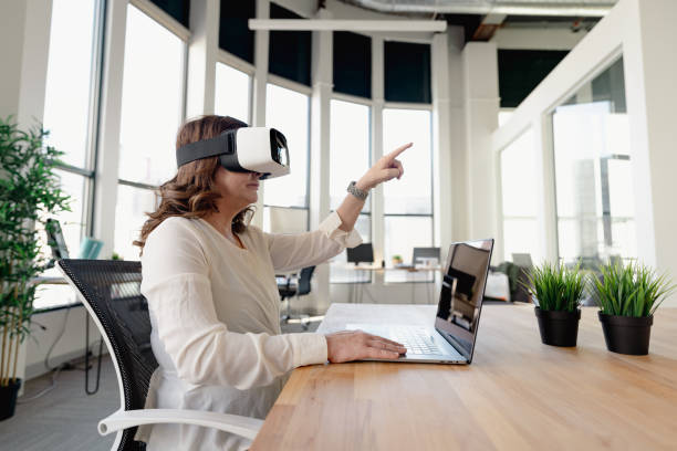 Senior woman in the office using VR glasses stock photo