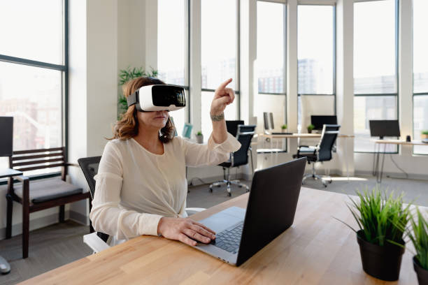istock Senior woman in the office using VR glasses 1365965733