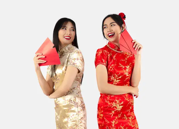Chinese new year concept Two Asian women in red traditional oriental costume holding red envelopes or Ang Pow isolated on white background.