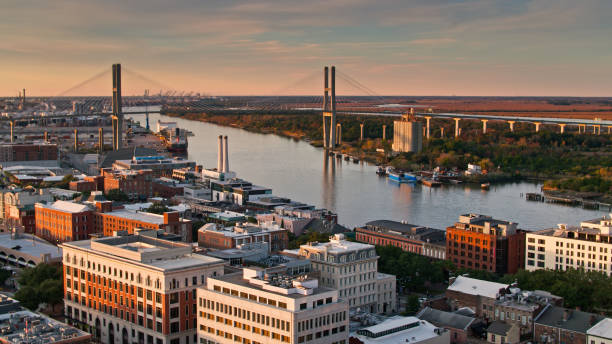 Drone Shot of Downtown Savannah and Talmadge Bridge Aerial shot of Savannah, Georgia at sunset, looking over downtown buildings towards the river, Talmadge Bridge and the distant silhouettes of cranes in the Port of Savannah. georgia us state photos stock pictures, royalty-free photos & images
