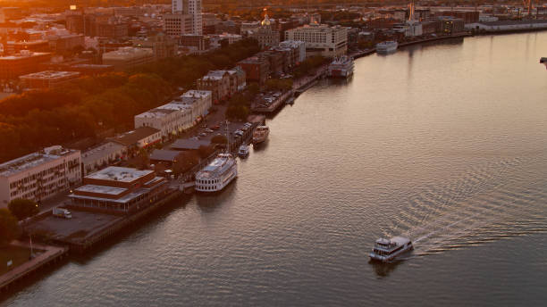 Boat on Savannah River at Sunset - Aerial Aerial shot of Savannah, Georgia at sunset, looking down on a boat passing the historic waterfront of the Savannah River. georgia us state photos stock pictures, royalty-free photos & images