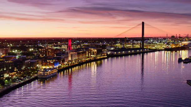 Historic Waterfront of Savannah, Georgia at Dusk - Aerial Aerial shot of the historic waterfront of downtown Savannah, Georgia after sunset, with a colorful purple sky reflecting in the water of the river. georgia us state photos stock pictures, royalty-free photos & images