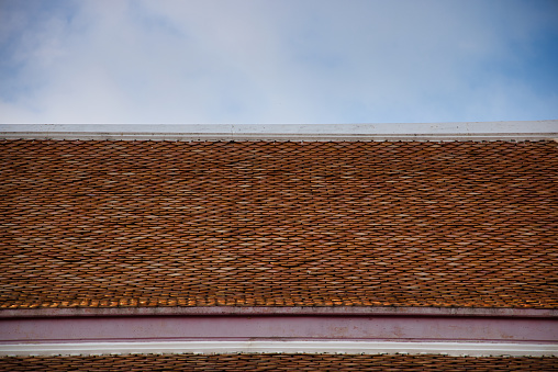 A perfectly tiled roof on a Buddhist temple in Asia. You can see the orange bricks and the cloudy sky very well!