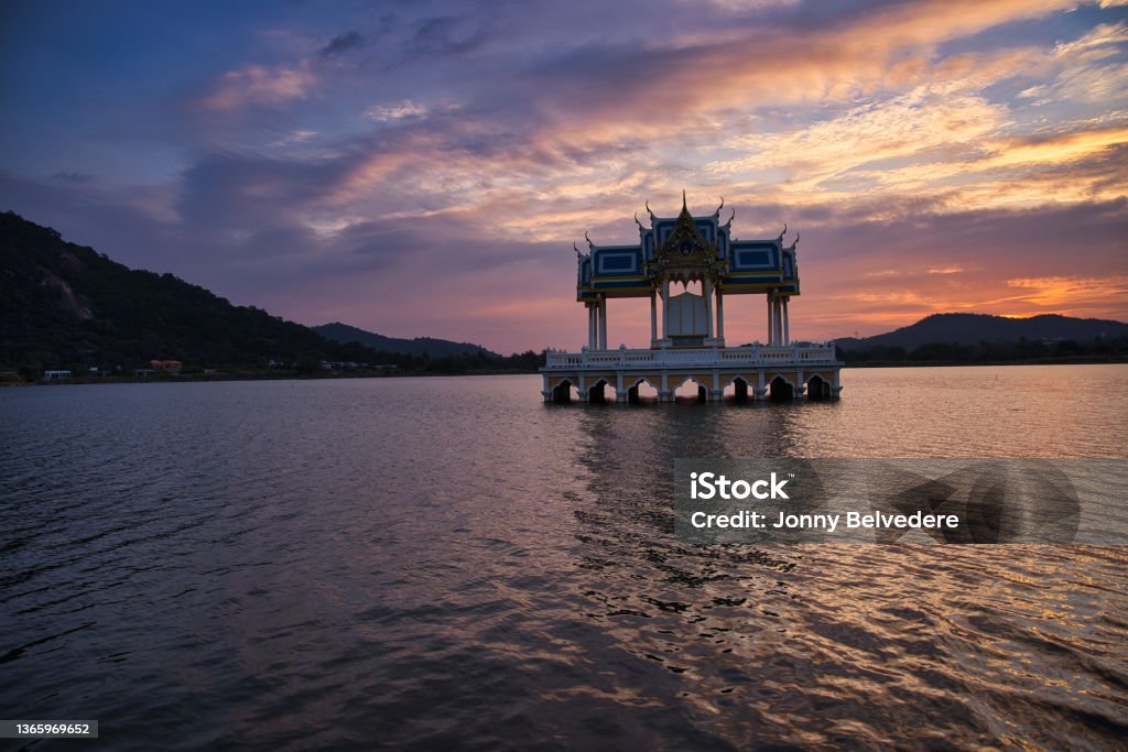 Buddhist Shrine On A Lake At Sunset! Buddhist shrine on a lake in Hua Hin in Thailand at sunset! The temple is reflected in the water and the sky turns red! Architecture Stock Photo