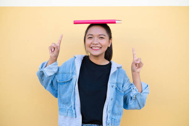 istock Happy student young girl with pink book on brown background. 1365970384