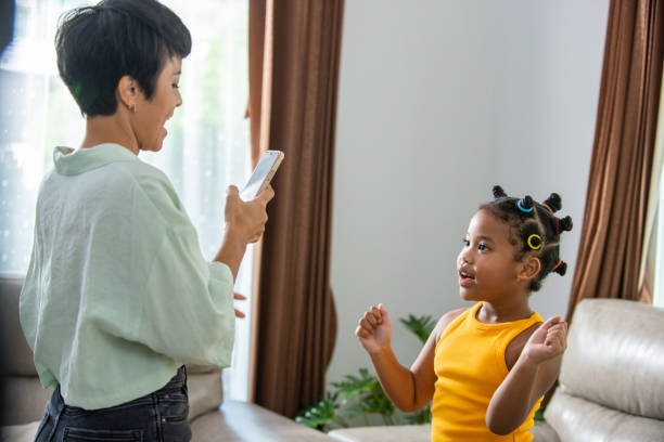 istock African mother using mobile phone making viral video live streaming with dancing little daughter 1365972147