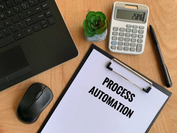 istock Process automation text written on paper with laptop, pen, calculator, mouse and brown table background. Business concept 1365977948
