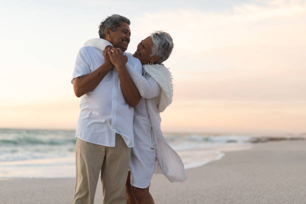 istock Cheerful newlywed senior multiracial couple looking at each other while embracing during sunset 1365978866