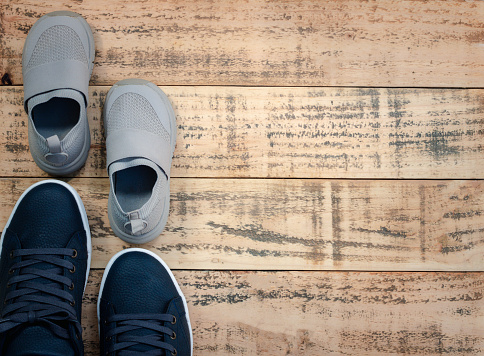 Big and small sneaker shoes on wooden background. Father's day celebration. Top-view composition.