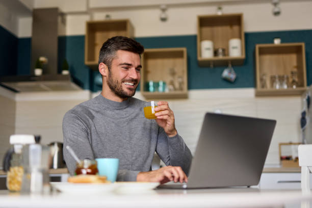 istock Young man making a video call on his laptop during breakfast 1365986069