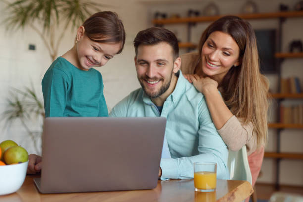 istock Happy family using laptop and making video call at home 1365986141