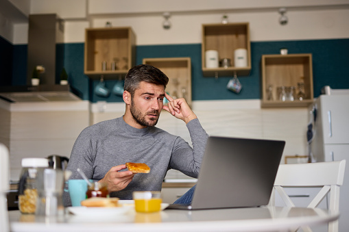 Young man making a video call on his laptop during breakfast