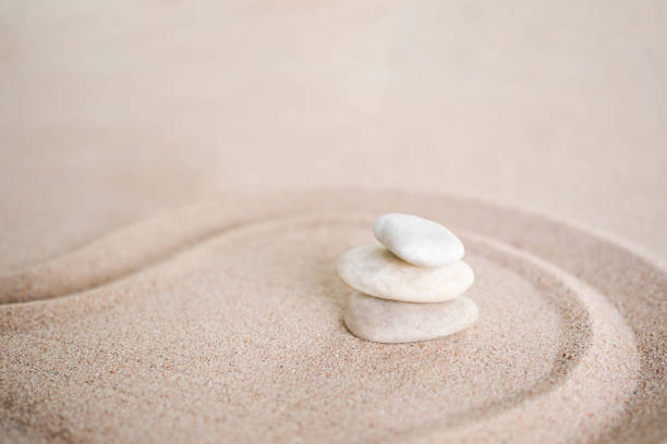 istock Stacks of pebbles with  pattern Zen japanese garden design on sand beach. Buddhism mind-scape calm stone symbols. 1365992104