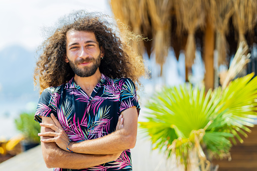 mixed race man with curly long hair outdoors ar sunny day.