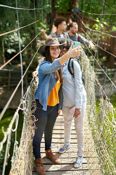 istock Friends crossing footbridge and taking selfie 1365997138