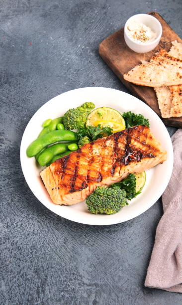 istock Baked salmon with vegetables on dark background. 1365998026
