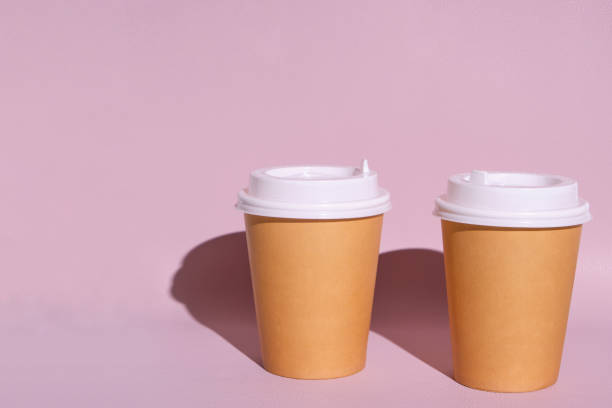 istock Disposable cups for hot coffee or tea on a pink background in the bright sun. 1365998592