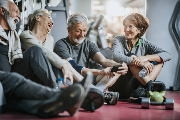 istock Happy senior couples using mobile phone on a break in a gym. 1365999803