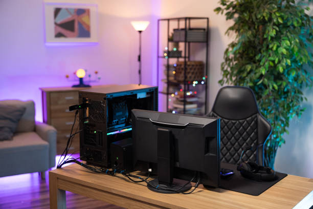 A backlit professional computer for a gamer. The monitor stands on a desk. The cozy room with modern design is lit with purple blue neon led lights A backlit professional computer for a gamer. The monitor stands on a desk. The cozy room with modern design is lit with purple blue neon led lights. neon bedroom stock pictures, royalty-free photos & images