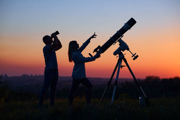 istock Couple stargazing together with a astronomical telescope. 1366003037