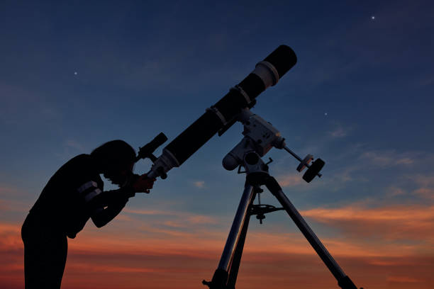 istock Girl with astronomical telescope stargazing under twilight sky. 1366003098