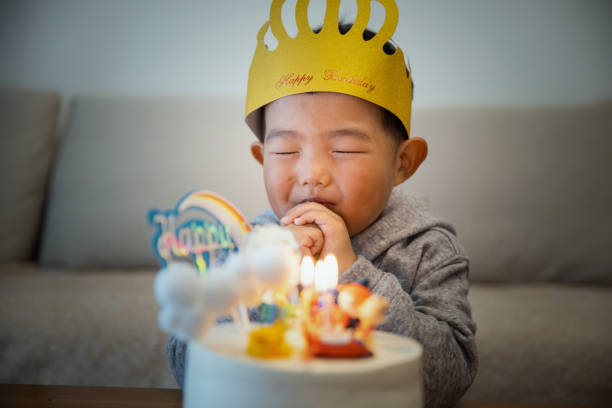 Little kid boy wishing with birthday cake