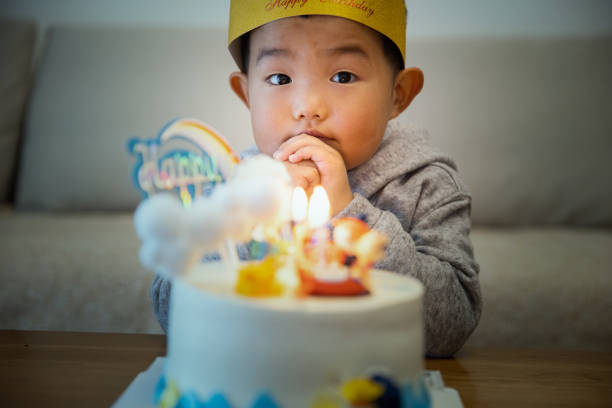 istock Little kid boy wishing with birthday cake 1366003906
