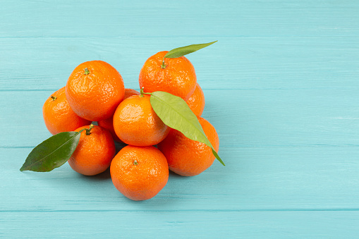 Heap of mandarins or tangerines on blue background with copy space