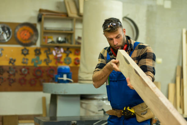 istock Young handsome caucasian carpenter checking the wooden board in old way 1366004722