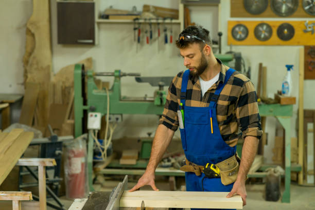 istock Handsome carpenter preparing, measures and cutting boards on cutting machine 1366004969