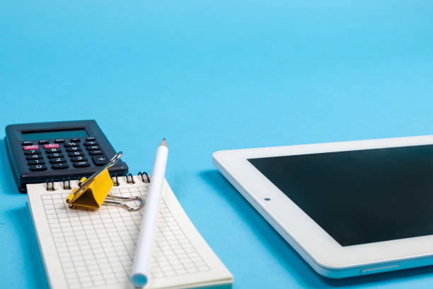 istock workspace top view. office Desk with office supplies, calculator and tablet computer. side view blue background 1366005392