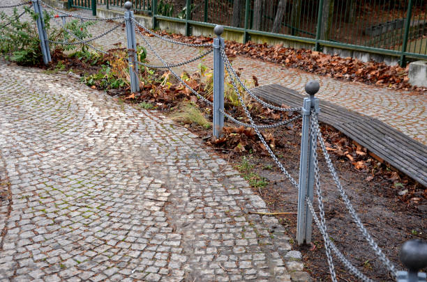 istock stone barriers in a square shaped cylinder with a hemisphere on top. granite curbs as stops at the parking lot. chain decorative fence against a colony of pedestrians and vehicles with a metal bollard 1366008366