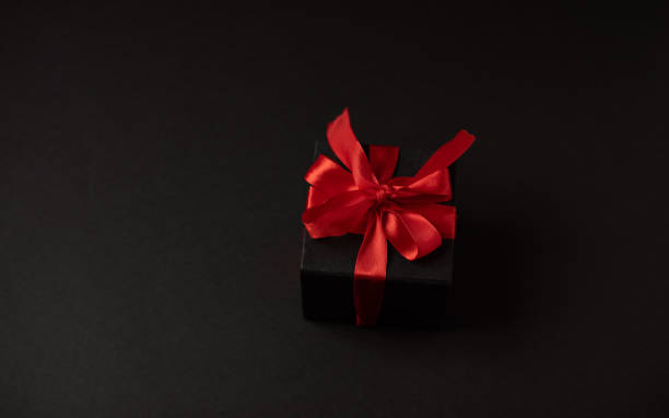 istock Black gift boxes with red ribbon on dark background with copy space for text. 1366009664