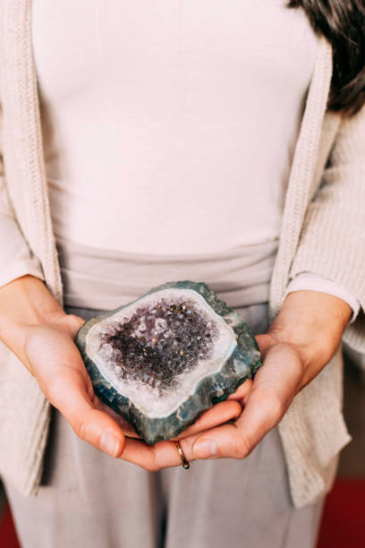 mujer sosteniendo geoda de amatista en interiores - amethyst esoteric mineral the natural world fotografías e imágenes de stock